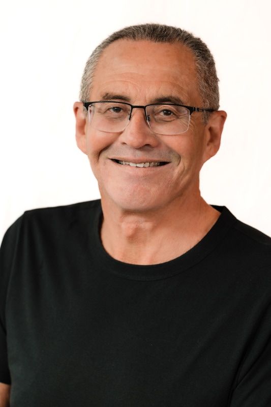 Smiling man with glasses in a black shirt.