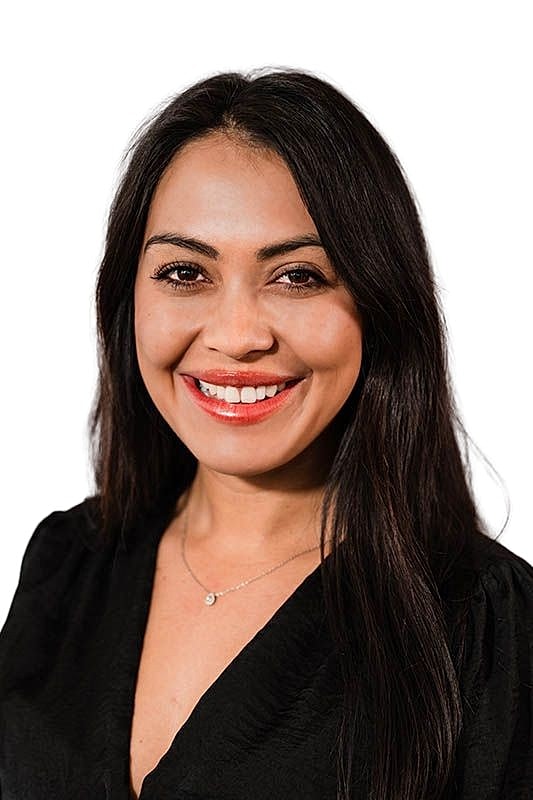 Smiling woman in front of skincare products.