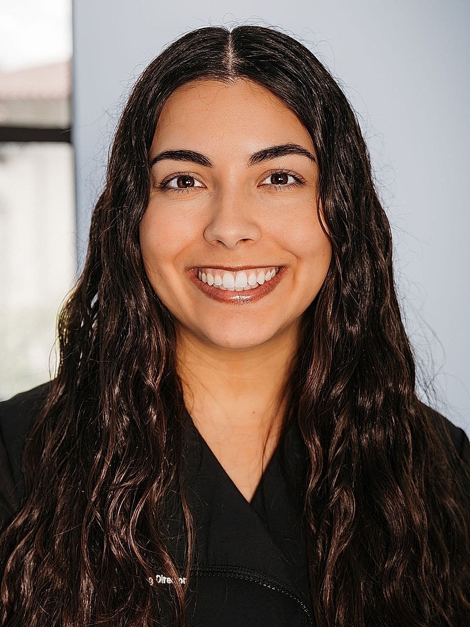 Smiling woman with long, wavy hair in attire.