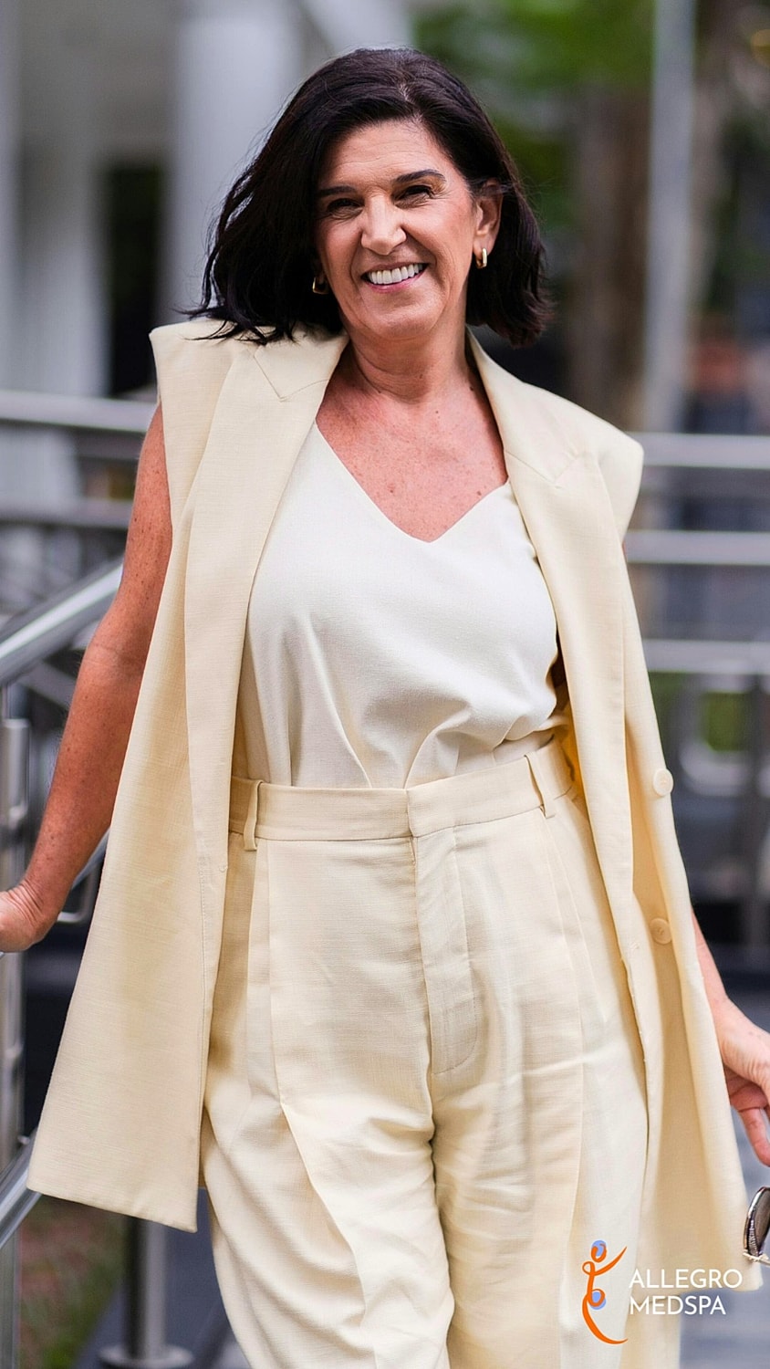 Smiling woman in stylish neutral-colored outfit.