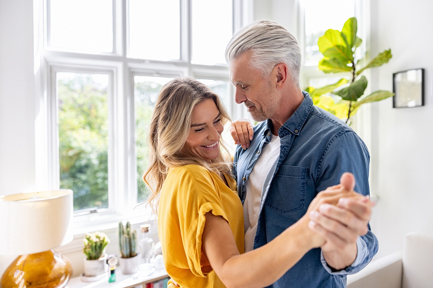 Emsella couple dancing and smiling in bright room.
