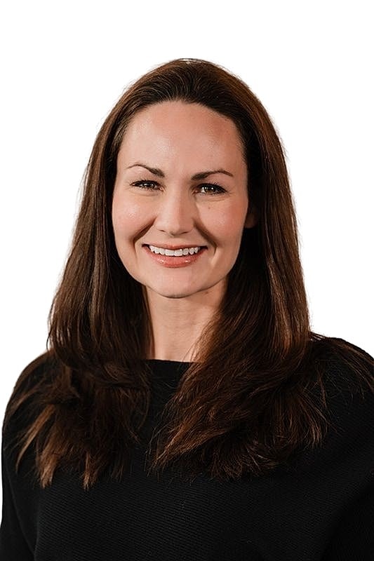 Smiling woman in black shirt against white background.