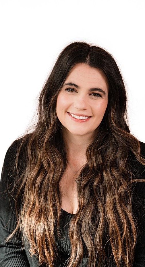Woman with long hair smiling softly at camera.