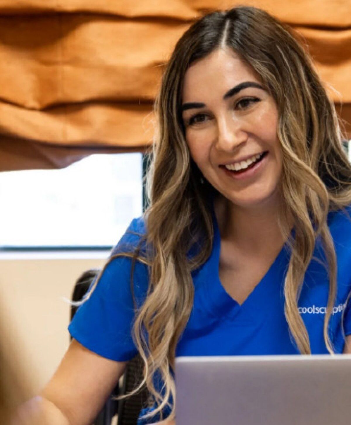 Smiling woman in blue medical scrubs working.