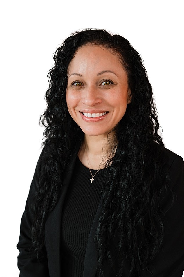 Smiling woman with curly hair in black blazer.